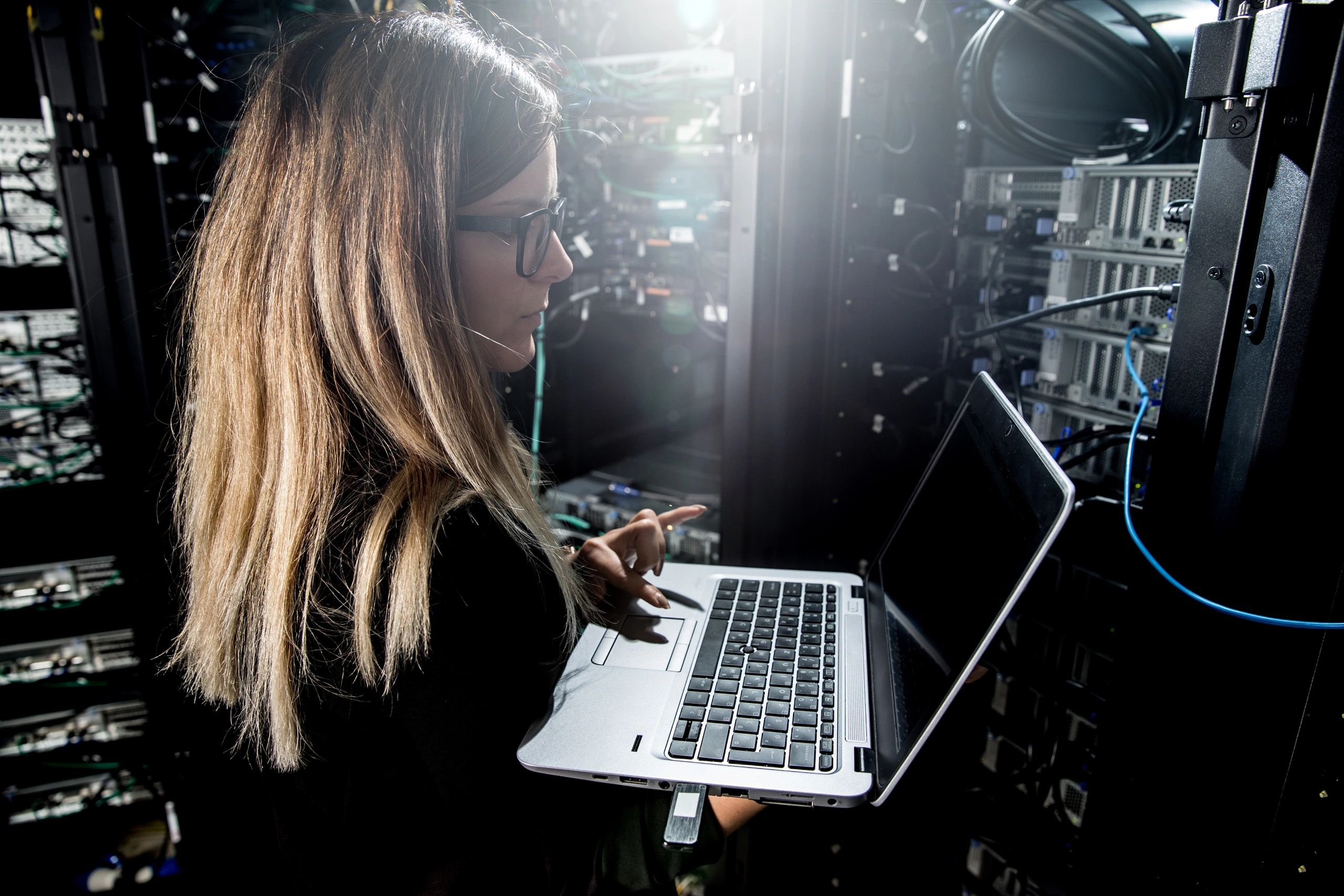 Técnica de soporte TI trabajando con laptop en sala de servidores